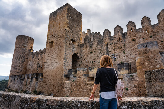Tourist woman contemplating the medieval castle from the wall that surrounds the village, Frias, Burgos.