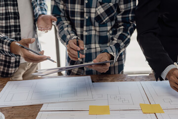 Engineer points to building on blueprint and uses laptop to draw building design project in office Image engineer concept of engineer meeting for architectural project Work with partners