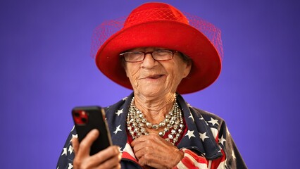 Closeup of toothless funny old grandmother wearing glasses and US flag jacket having video chat on...