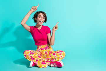 Full length photo of impressed cute woman dressed flower print trousers showing two fingers empty space isolated teal color background