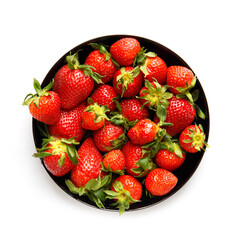 Berries of organic strawberries in a black round plate isolated on white background, top view.