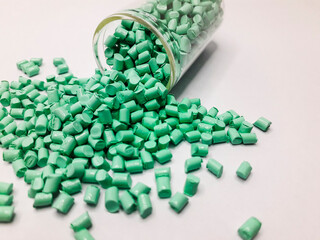 Mint green masterbatch granules with glass tube isolated on white background, this polymer is a...