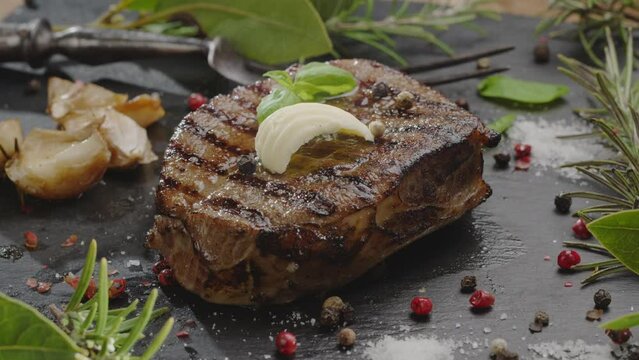 Cooked grilled ribeye steak on a gray serving stone with a stick of butter and steam emanating from it. Great food background for your projects.