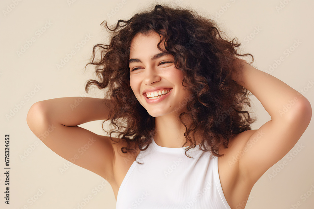 Wall mural Beautiful young woman with black curly hair in white sleeveless top smiling standing by the window. Sunlight. Banner for beauty skin body care bio eco cosmetics concept - Wall murals