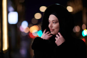 Muslim woman walking on an urban city street on a cold winter night wearing hijab