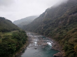 a body of water near some mountains under clouds and snow