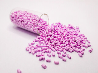 candy pink masterbatch granules with a glass tube isolated on a white background, this polymer is a...