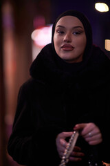 Muslim woman walking on an urban city street on a cold winter night wearing hijab