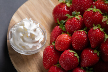 photo of ripe strawberries and cream on a wooden board