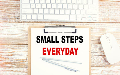 SMALL STEPS EVERYDAY text on a clipboard on wooden background
