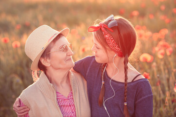 Portrait of a beautiful grandmother and granddaughter in the poppy field.
