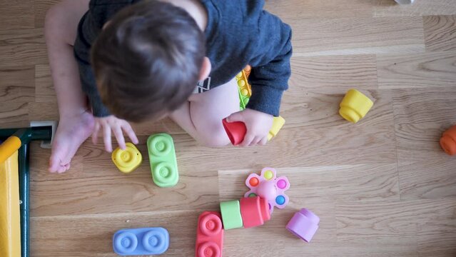 Child boy on the floor half-naked trying to fold constructors,Multi-colored constructor
