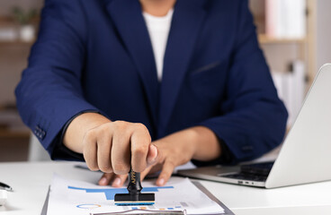 Close-up of a Businessman hand stamping with approved stamp on text approved document at desk, validates and manages business documents and agreements, Contract form paper. Approval stamp.
