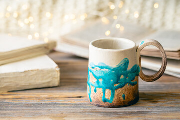 Handmade cup and books close-up on a wooden surface.