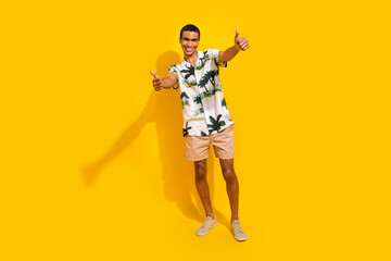 Full length photo of nice young male showing thumb up good quality wear trendy palms print garment isolated on yellow color background