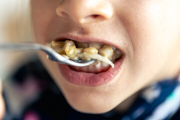 A girl eats porridge with fruits, close-up.