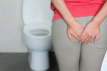 Abdominal pain woman holds her stomach with her hand. She has stomachache from diarrhea. Constipation concept. bathroom toilet background