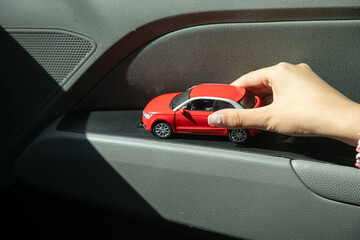 Caucasian female hand showing red toy car.