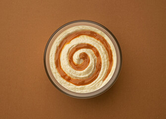 Cream cheese with caramel cream swirl on brown background, top view
