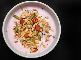 Plato de yogurt con frutos secos o mix de granola sobre un fondo negro aislado 