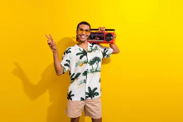 Foto op Plexiglas anti-reflex Photo portrait of nice young male have fun tape recorder v-sign dressed stylish palms print garment isolated on yellow color background © deagreez