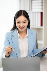 Asian businesswoman plans to analyze financial reports business plan investment financial analysis concepts Using laptop computer, documents, calculator on table in office