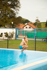 A seven-year-old boy of European appearance jumps into the pool