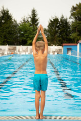 A seven-year-old boy of European appearance jumps into the pool