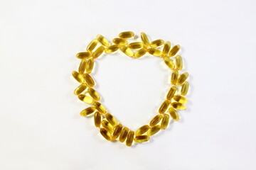 heart shape fish oil or linseed oil vitamin pills,gelatin capsule or tablet for health,heart health,medical,ayurvedic,phrmacy,naturopathy related concept in white background,top view,copy space