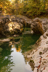 Fototapeta premium Felsenschlucht im Herbst in schönem Licht, der Himmel und die bunt gefärbten Bäume spiegeln sich im ruhigen Wasser
