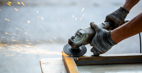 Grinding machine at work. Sparks fly from under the grinders, men's work. Dark background with copy...