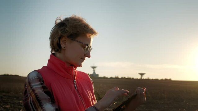 Woman operator equipment tablet pc controls solar radio telescope antennas. Wide view footage