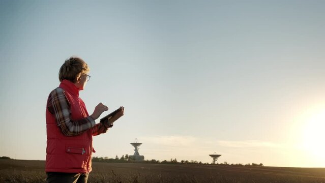 Woman operator equipment tablet pc controls solar radio telescope antennas. Wide footage