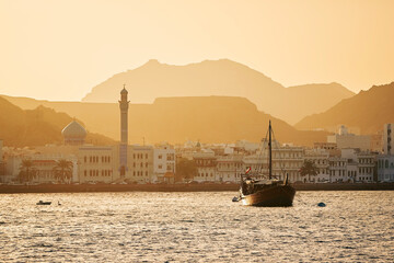 Harbor with traditional wooden boat Dhow and waterfront of old town in Muscat. Sultanate of Oman..