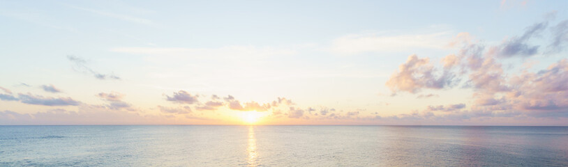 Calm dawn sea panoramic background. Morning sun and blue sky with colorful clouds.