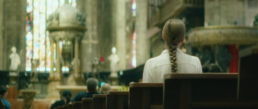 Pilgrim woman visiting cathedral church. Parishioner sitting on pew bench. Girl looking for God in the Temple.