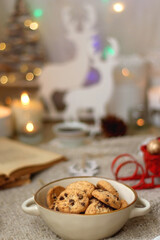 Various colorful Christmas decorations, soft blanket, cup of tea, sweet snacks and lit candles on the table. Cozy Christmas atmosphere at home. Selective focus.
