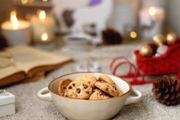 Various colorful Christmas decorations, soft blanket, cup of tea, sweet snacks and lit candles on the table. Cozy Christmas atmosphere at home. Selective focus.