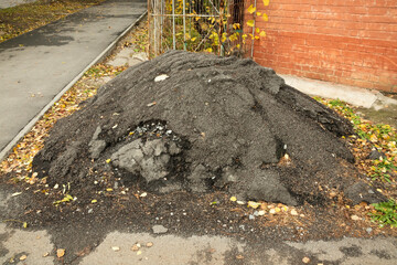 Heap of hardened asphalt on the street. Problem with asphalt laying and city pollution