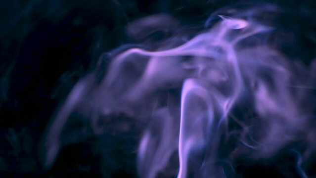 Slow motion video shooting of purple smoke on black background. Abstract background of incense, patterns and waves
