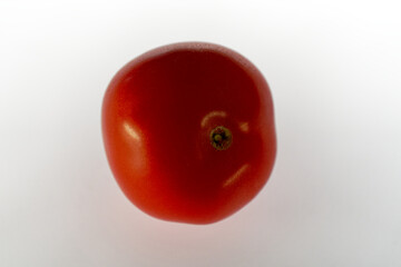 Close-up of red tomato with reflections against white illuminated background . Photo taken November 8th, 2023, Zurich, Switzerland.