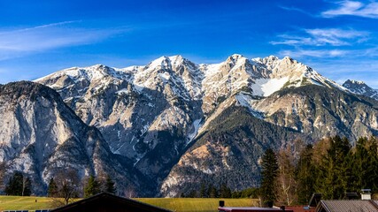 the mountain is covered with snow and green grass, but no trees are present in