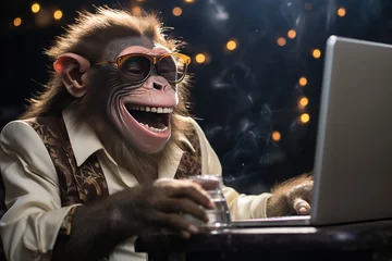 Gartenposter The muzzle of a laughing monkey sitting at a laptop. Communication online. Joke, humor. © BetterPhoto