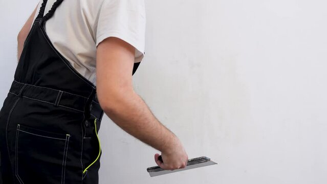 Work aligns with a spatula. Process putty concrete wall with a metal spatula. Repair of a room