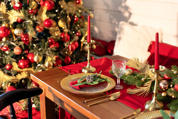 Festive table setting for Christmas dinner at home. Holiday Served table with decorations, candles and garland. Beautiful table setting with Christmas decorations and dishware in living room.	
