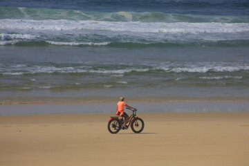 Fototapeta premium Frau fährt mit dem Fatbike am Strand des atlantischen Ozean