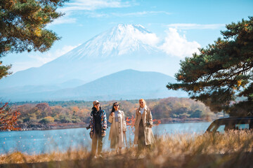 Attractive girl friends happy and fun together while travel Mt.Fuji landscape view and looking beautiful red maple tree leaf falling in autumn, Happy Asian woman travel in Japan on holiday vacation - obrazy, fototapety, plakaty
