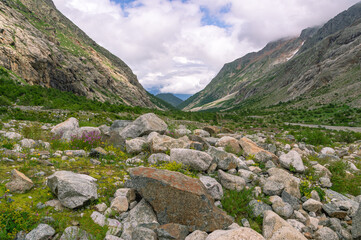 Fototapeta na wymiar Panorama of a gorge in a mountainous area. Granite stones in the mountains. Landscape in summer with views of mountains, clouds and flowers. Hiking in the mountains. A trip to the mountains.