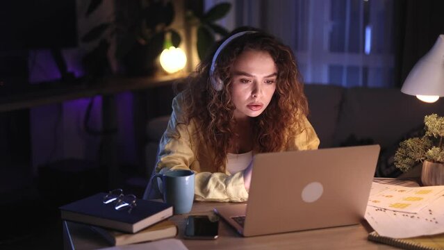 Tired freelancer having remote work on laptop checking email surfing web and drinking hot coffee or tea at night Busy young woman student having online distance education on computer at home workplace