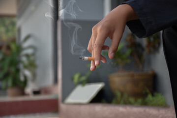 Closeup hand holding lighted cigarrette smoking of asian boys who starting to smoke in private area...